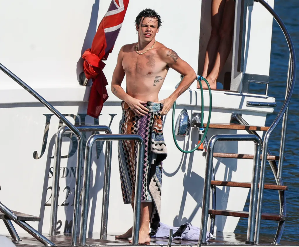 Yungblud on a yacht in Sydney, wearing a patterned towel.