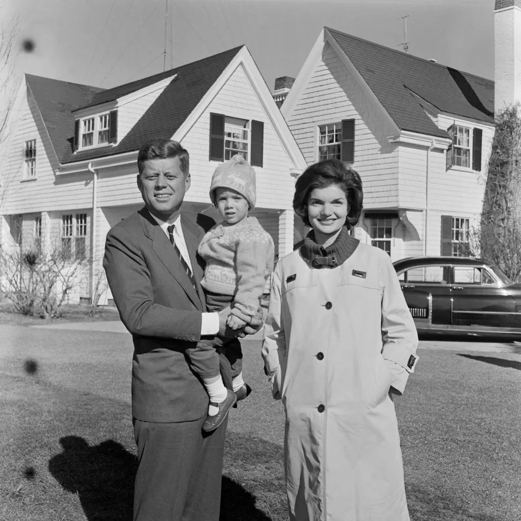 John F. Kennedy holding his daughter Caroline, standing beside Jacqueline Kennedy in front of their home in Hyannis Port, Massachusetts, on election day.