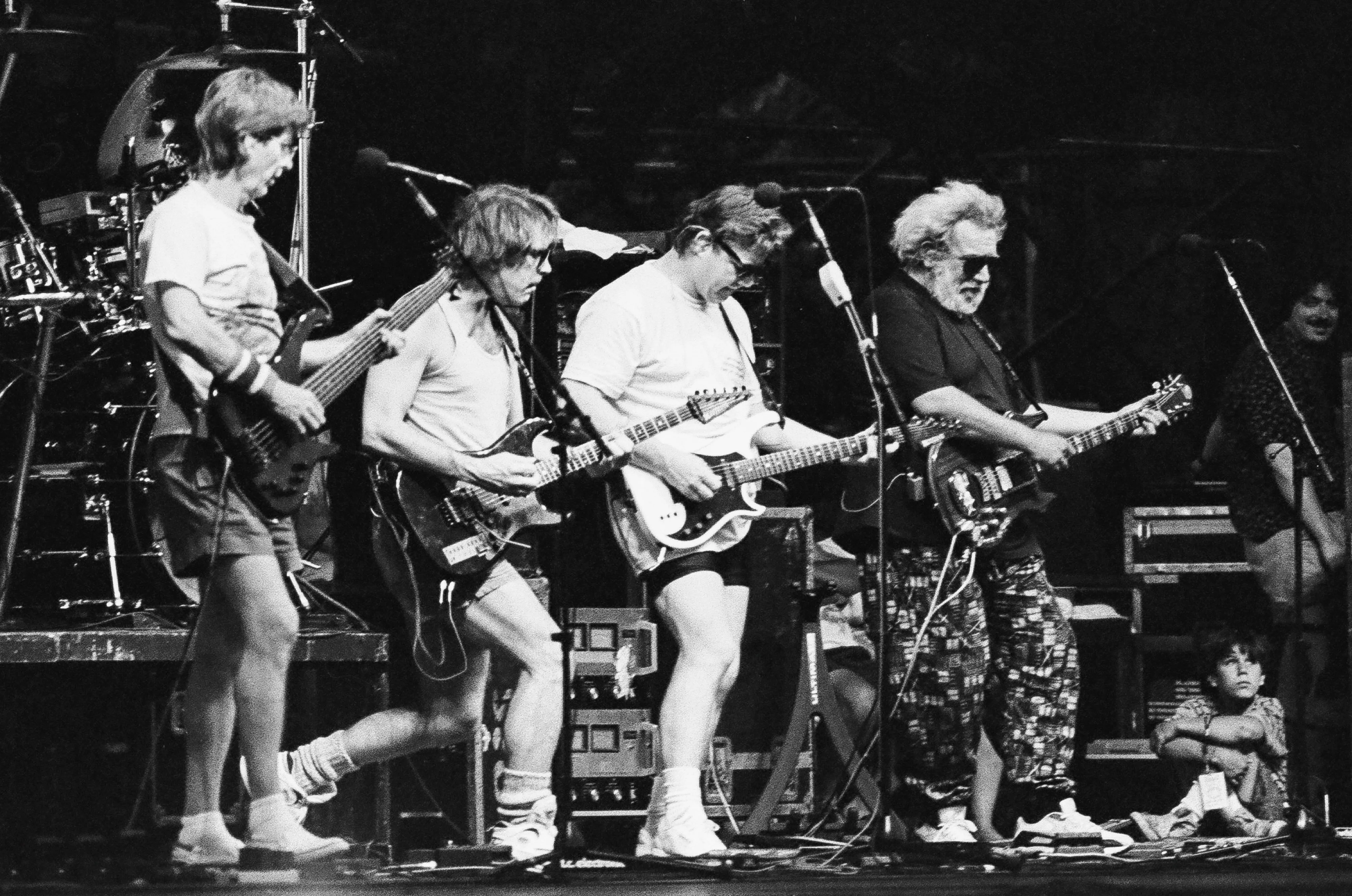 Four members of the Grateful Dead band perform on stage.