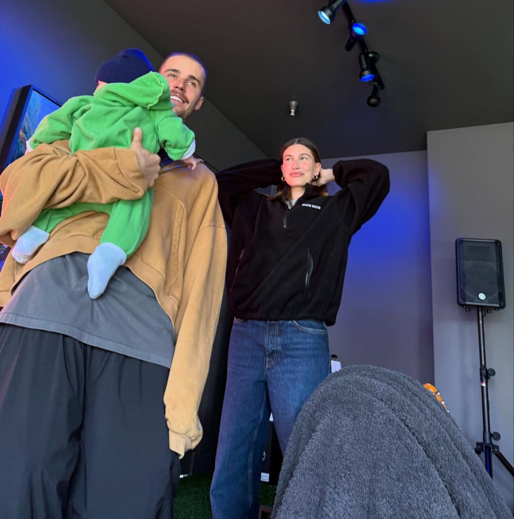 Justin Bieber holding a baby, with Hailey Bieber standing next to him.