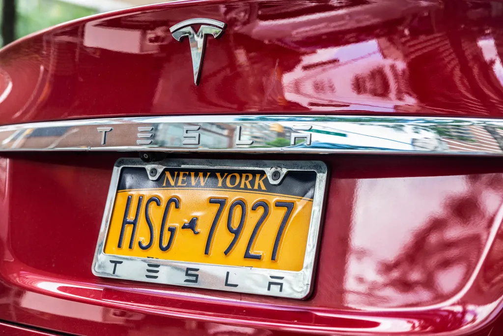 Red Tesla car parked in New York City with a New York license plate.