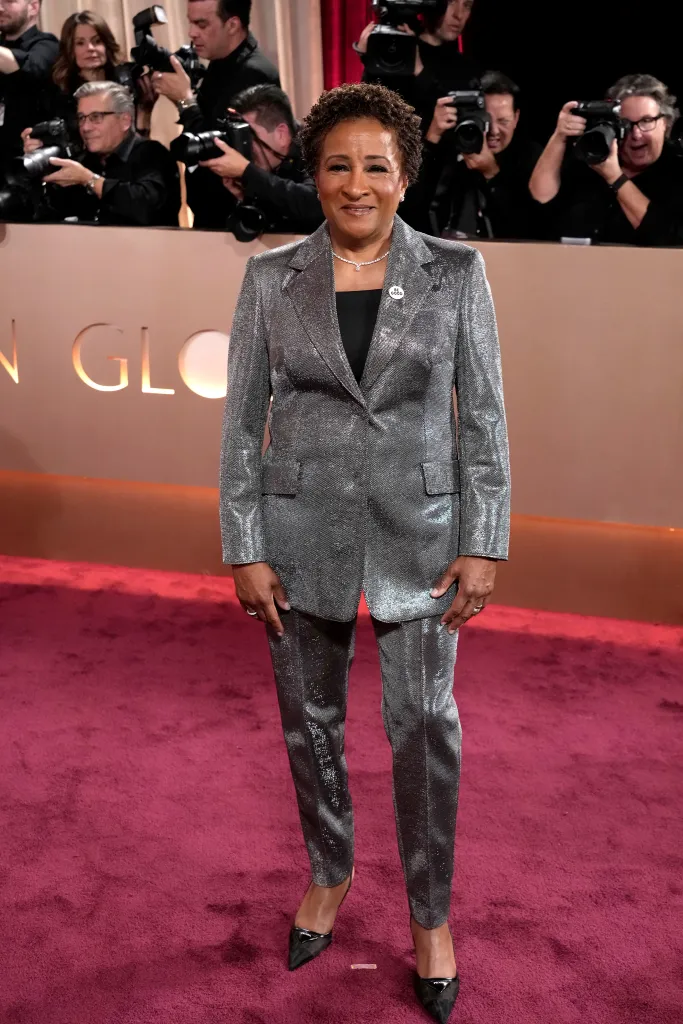 Wanda Sykes in a silvery suit on a red carpet at the 83rd Annual Golden Globe Awards.