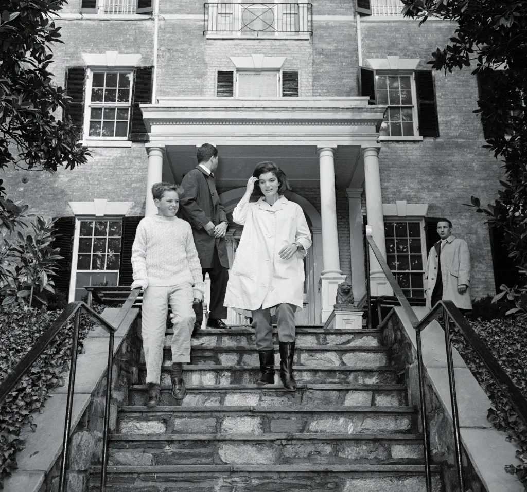 Jacqueline Kennedy walks down steps of her Georgetown home with Joe Kennedy Jr. and two unidentified men.