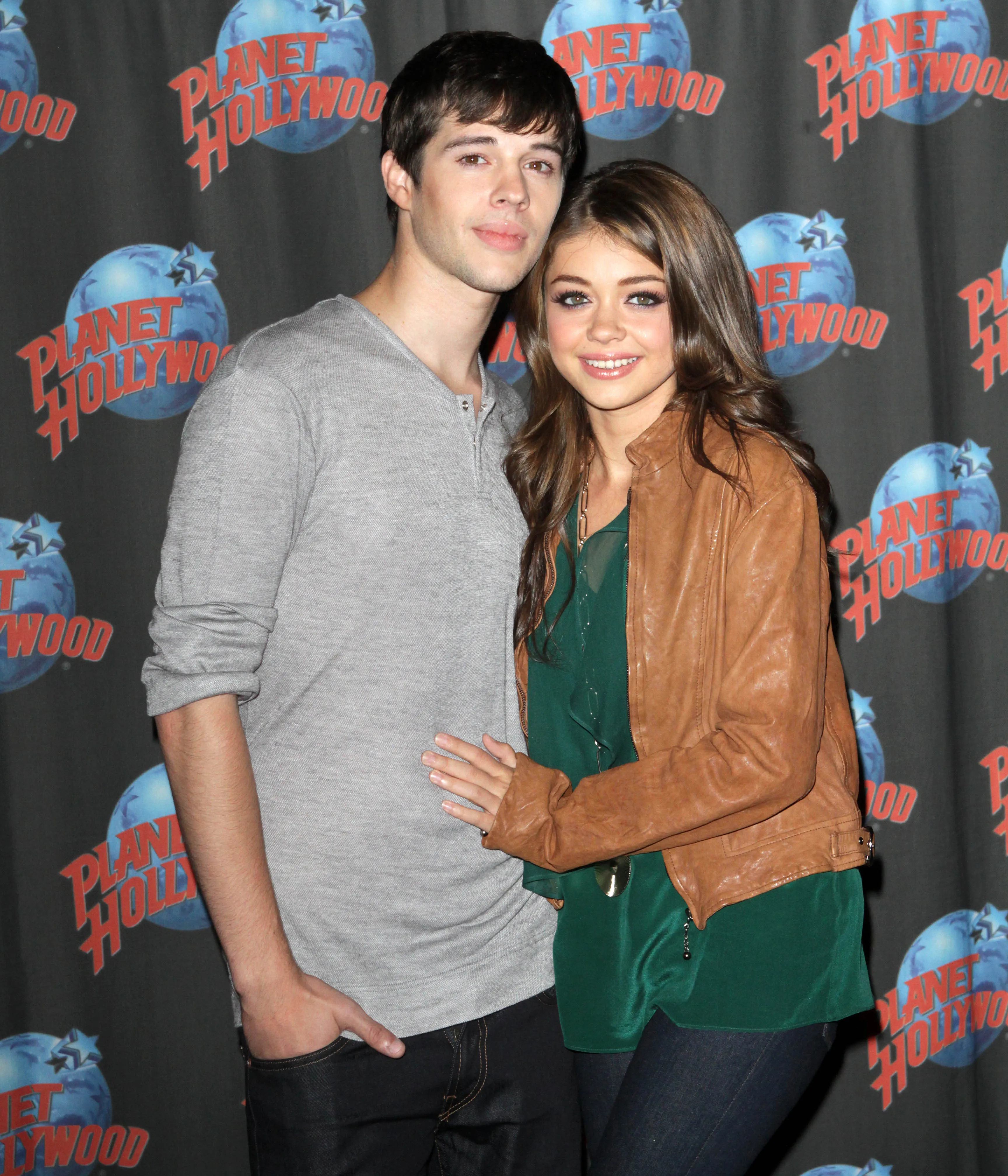 Sarah Hyland and Matt Prokop pose together against a backdrop with the Planet Hollywood logo.