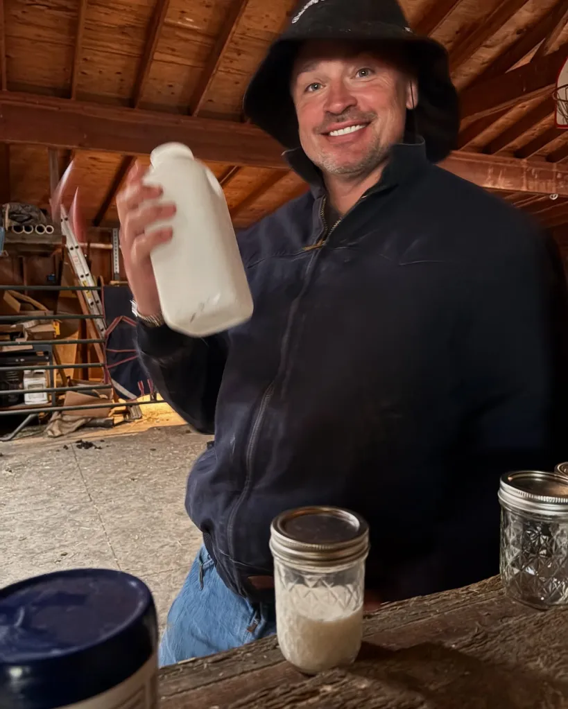 Tom Welling smiling and holding a bottle of milk.