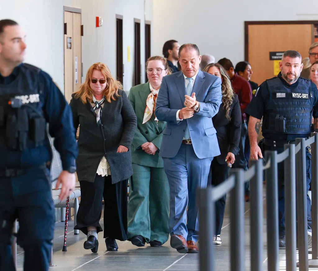 Asa Ellerup and her daughter Victoria Heuermann walking through a courthouse with security and legal team members.