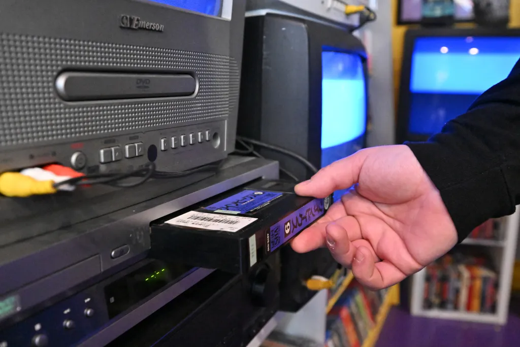 A person inserting a VHS tape into a VCR.