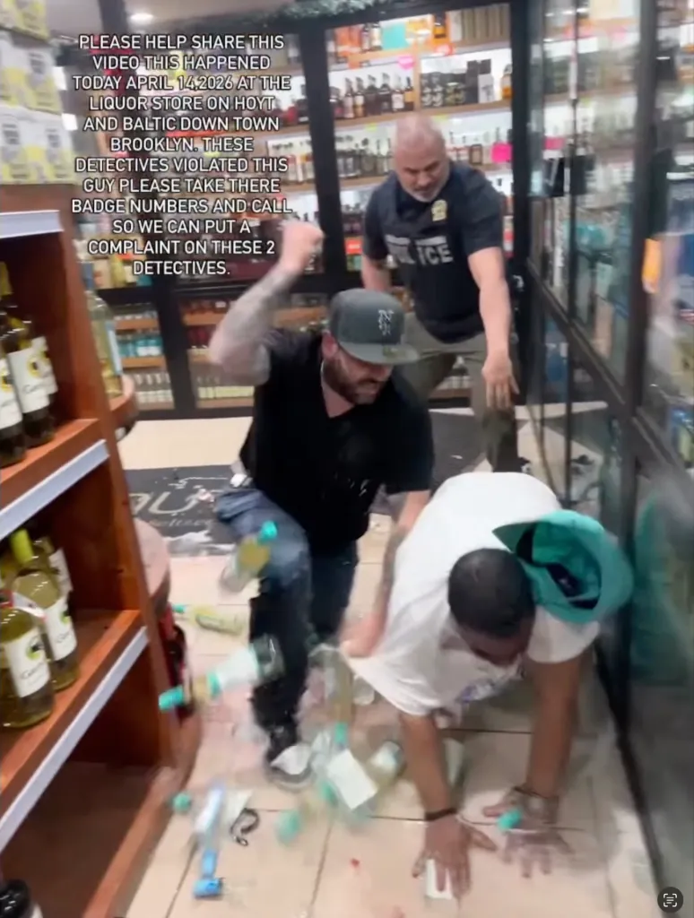 Two men in plainclothes attempting to arrest a third man in a liquor store, with bottles broken on the floor.
