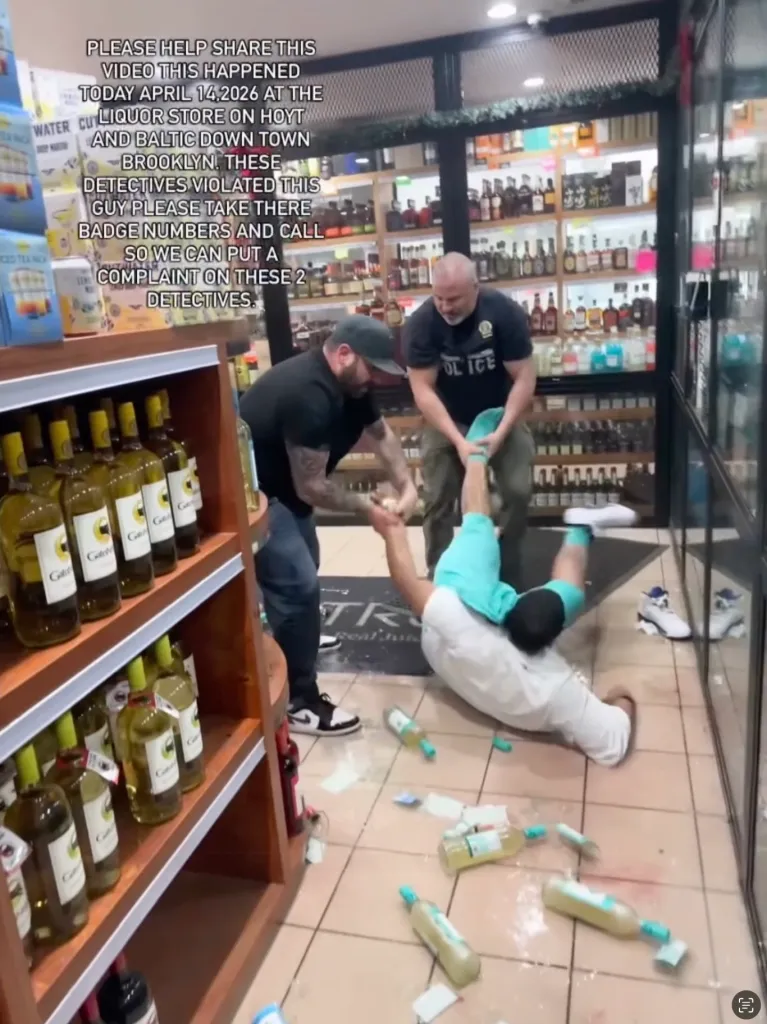 Two undercover detectives arrest a man inside a liquor store, with several bottles broken on the floor.
