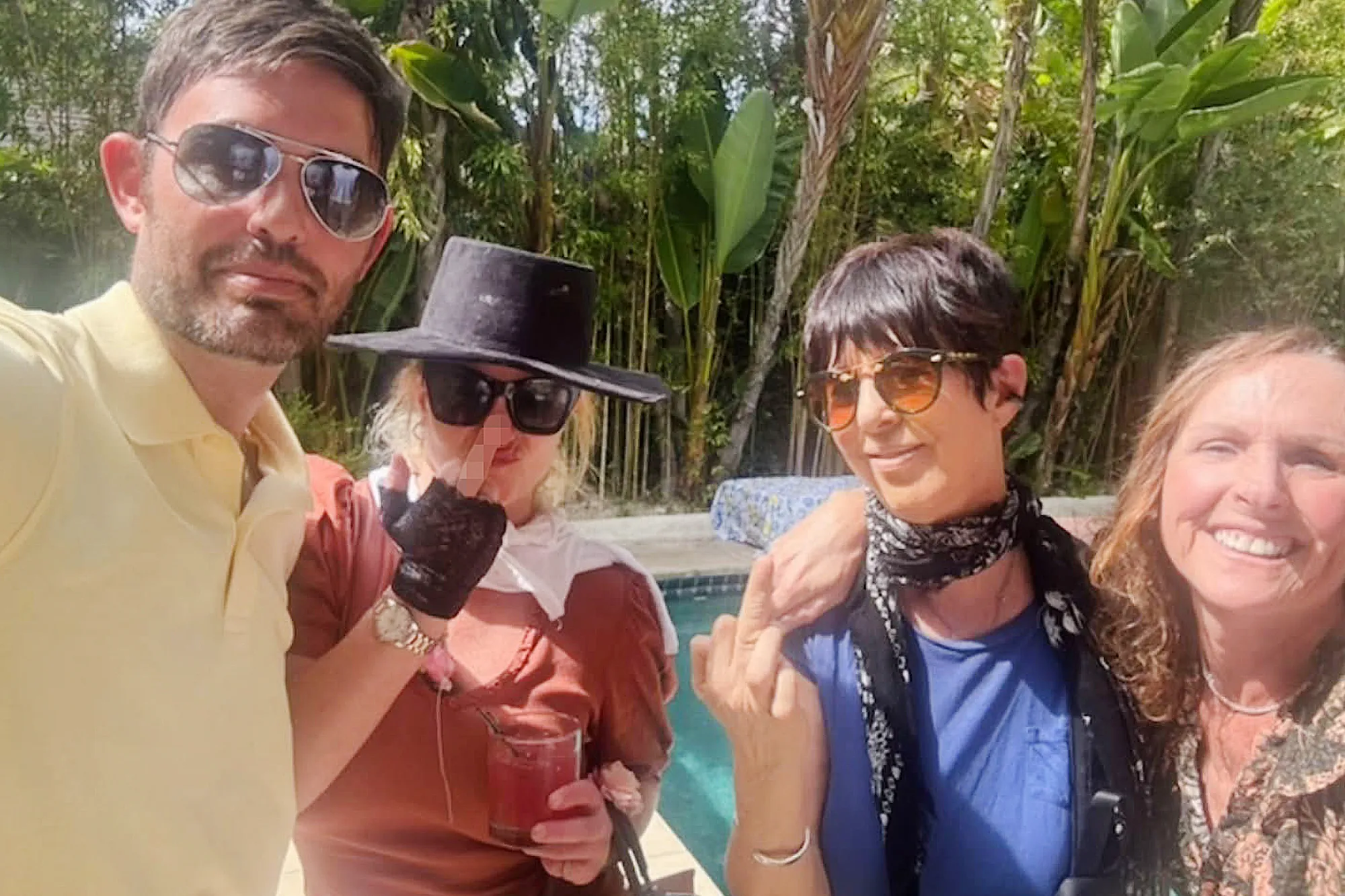 Four people posing for a group photo next to a swimming pool.