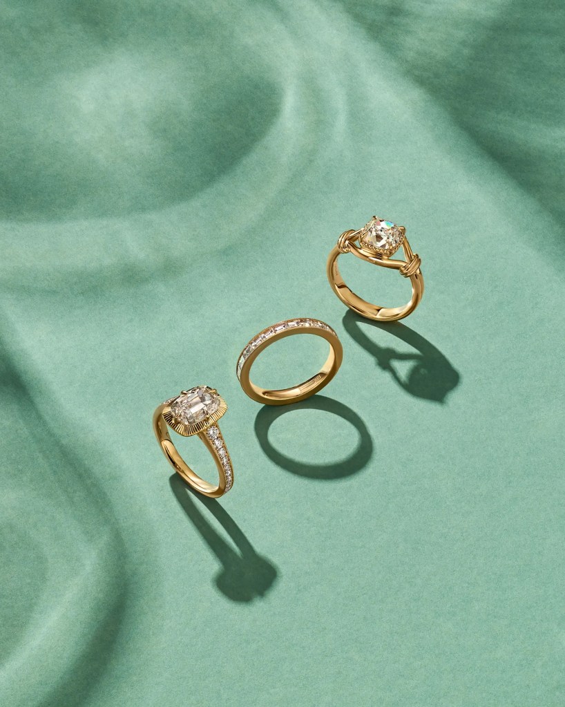 Three gold and diamond rings on a pale green surface.