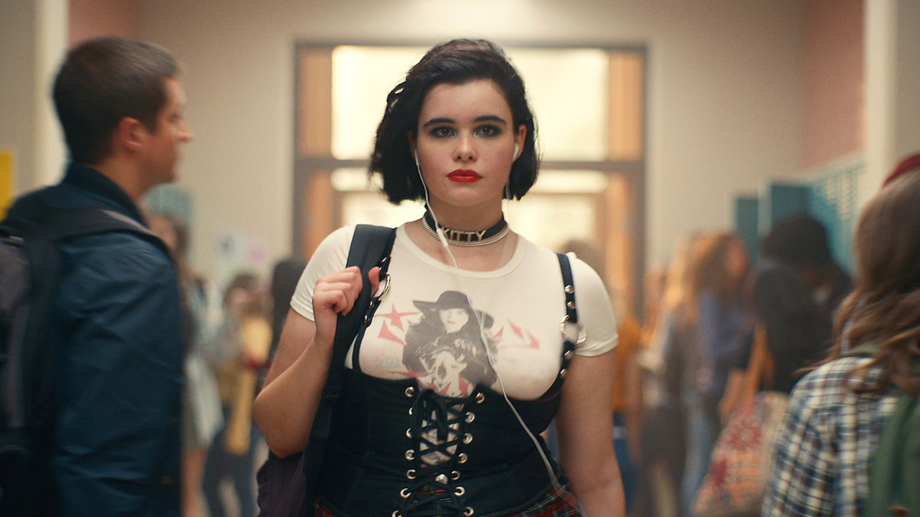 Kat Hernandez in a white t-shirt and black corset in a school hallway.