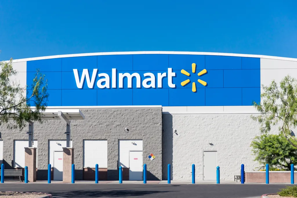Exterior of a Walmart store with its blue and yellow logo visible against a bright blue sky.