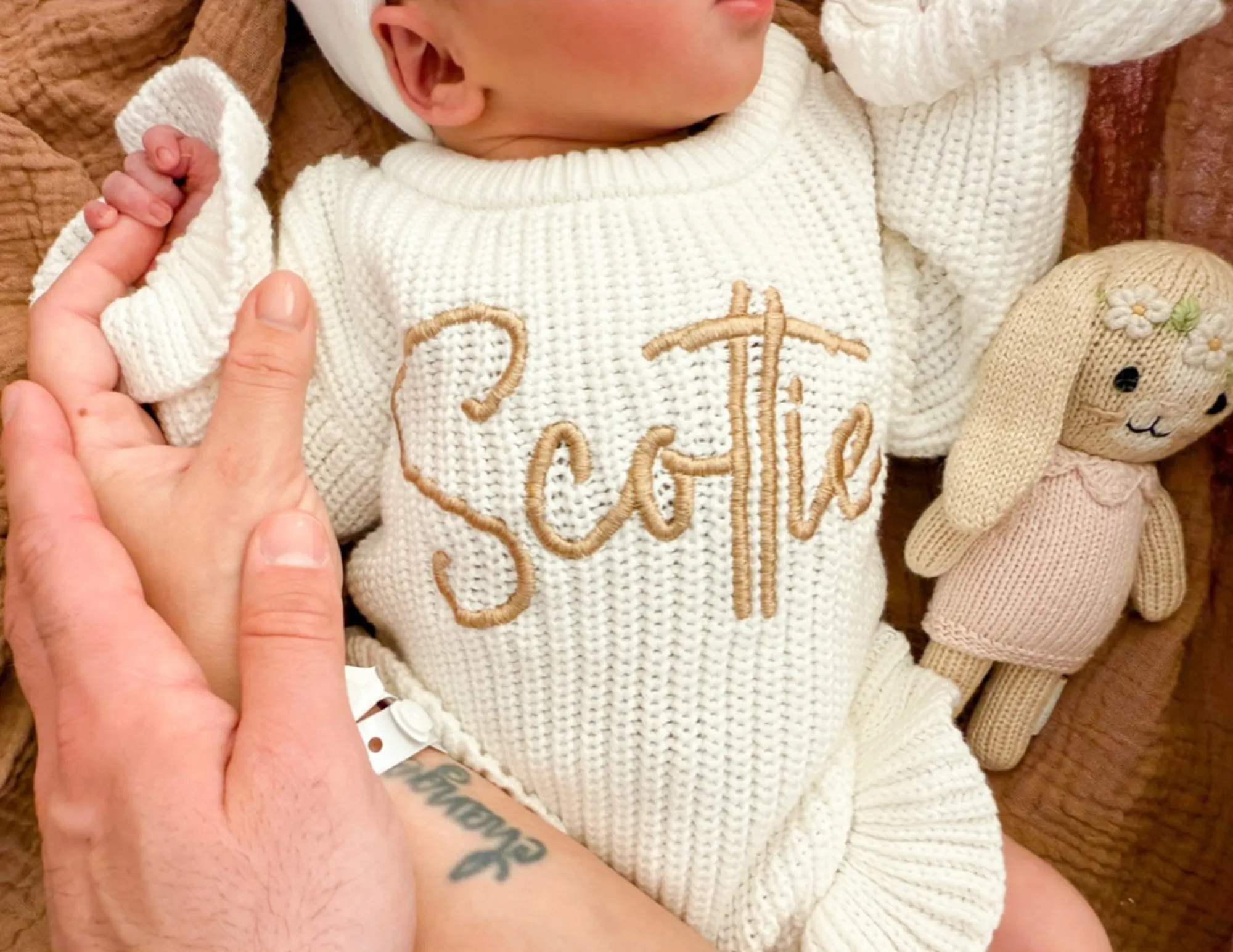 Newborn baby in white knitted outfit with 