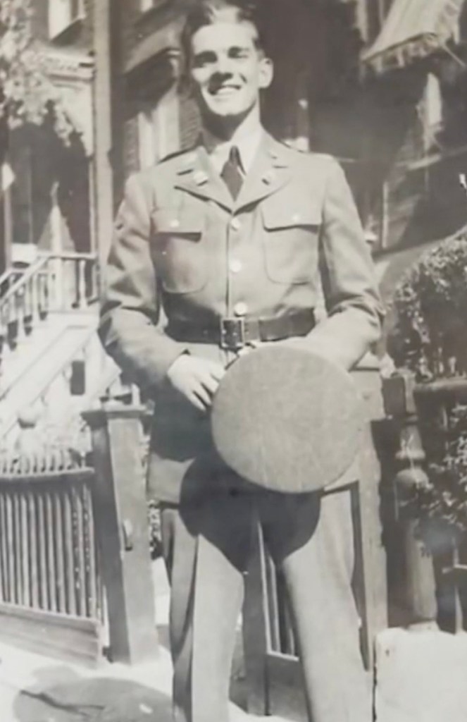 Smiling man in military uniform holding a hat.