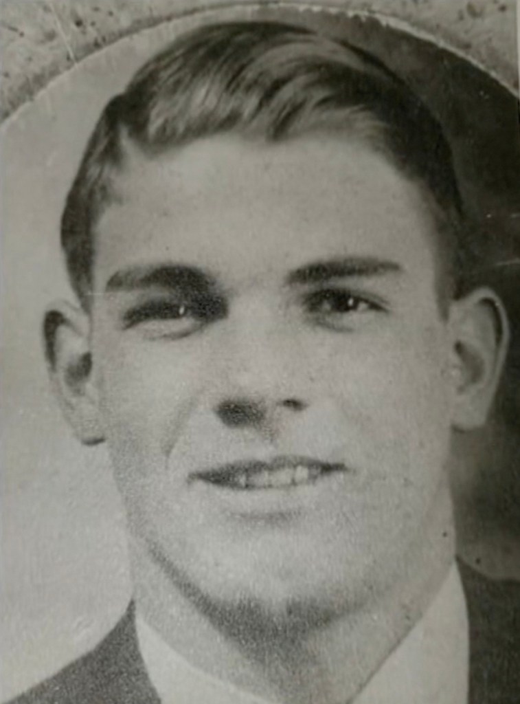 Black and white photo of a smiling young man in a suit.