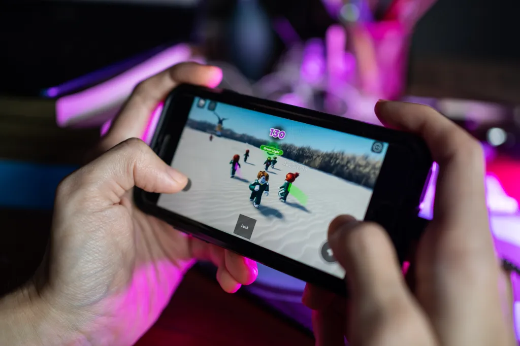 A person playing a Roblox game on an iPhone 7.