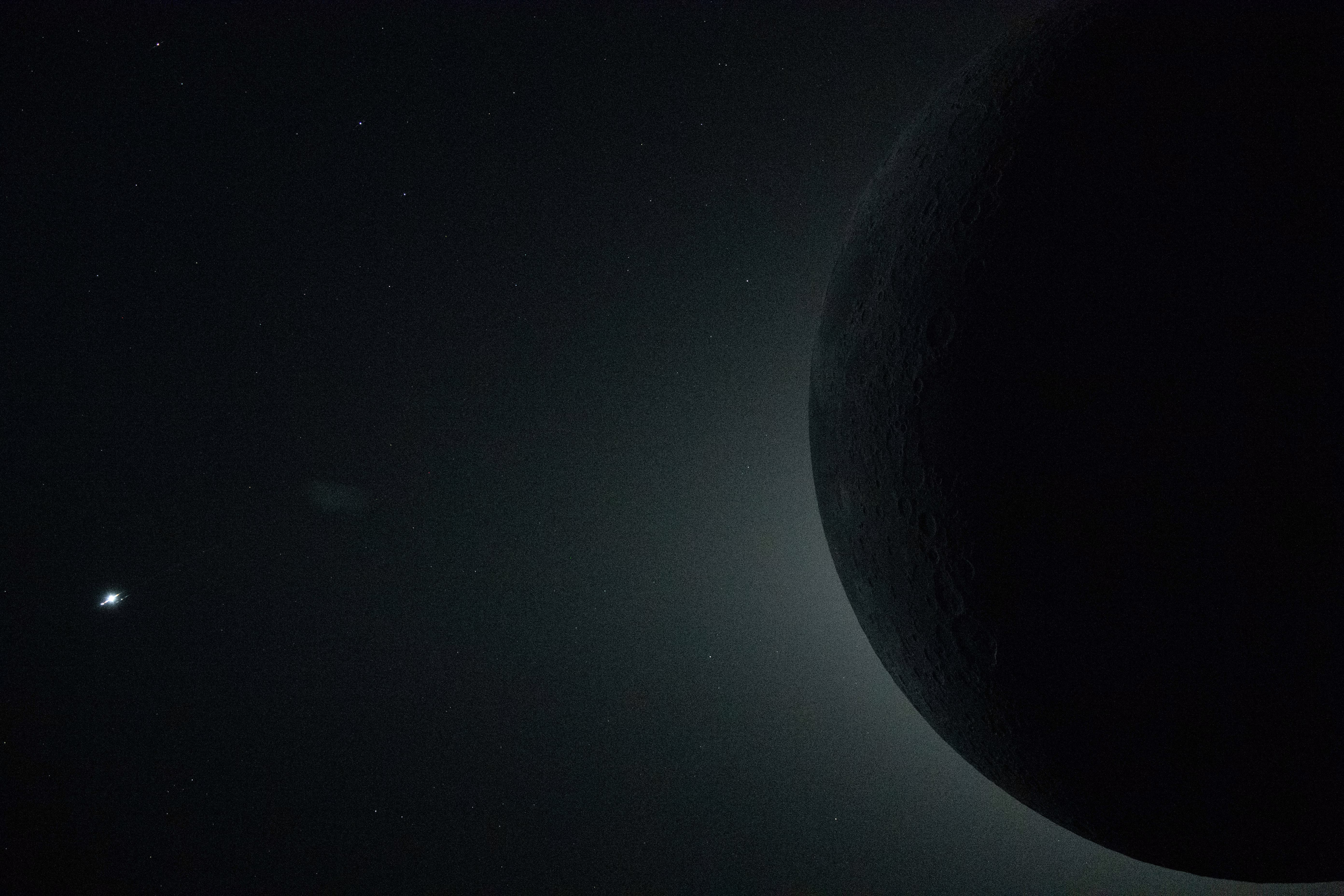 A close-up view of the moon, seen from the Orion spacecraft, during an eclipse, silhouetted against the glowing corona of the sun