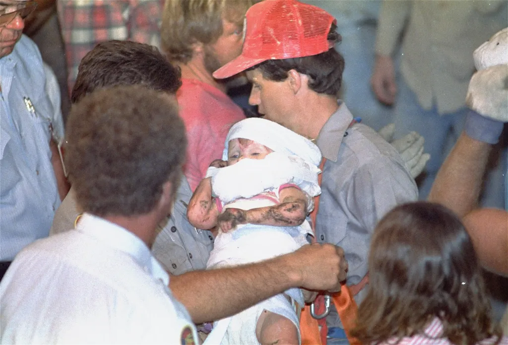 Rescue worker Steven Forbes holds 18-month-old Jessica McClure after she was rescued from a well.