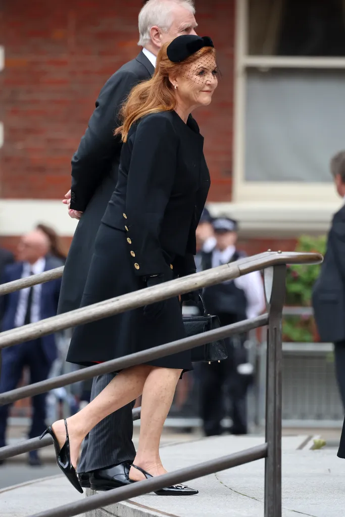 Sarah Ferguson, Duchess of York, in a black coat and veiled hat, walks past a railing at the funeral of The Duchess of Kent.