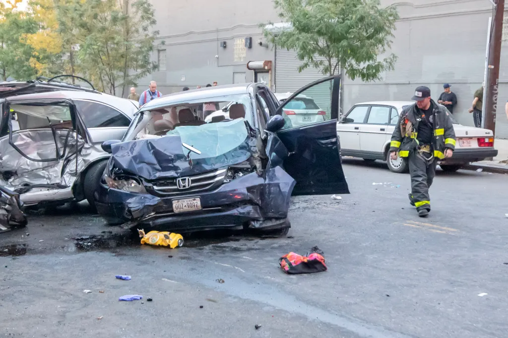 A firefighter walks past two heavily damaged cars after an accident in the Gowanus neighborhood of Brooklyn.