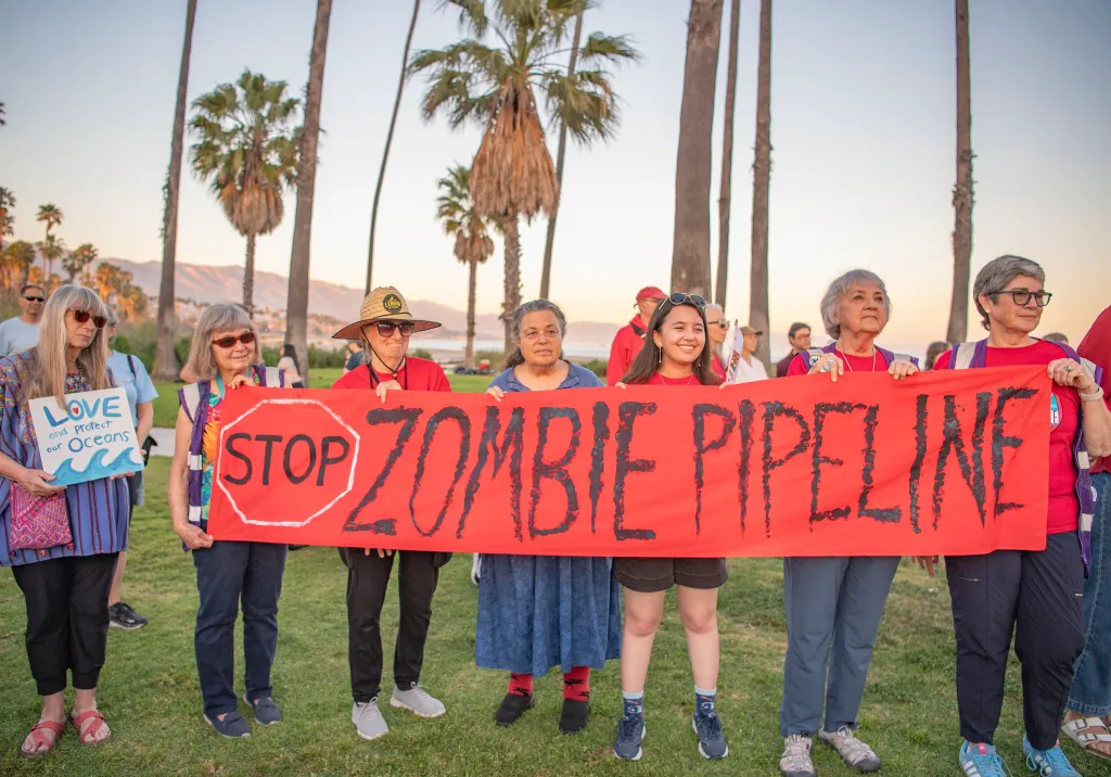 People protesting the Sable Oil Pipeline with a red banner that reads "STOP ZOMBIE PIPELINE."