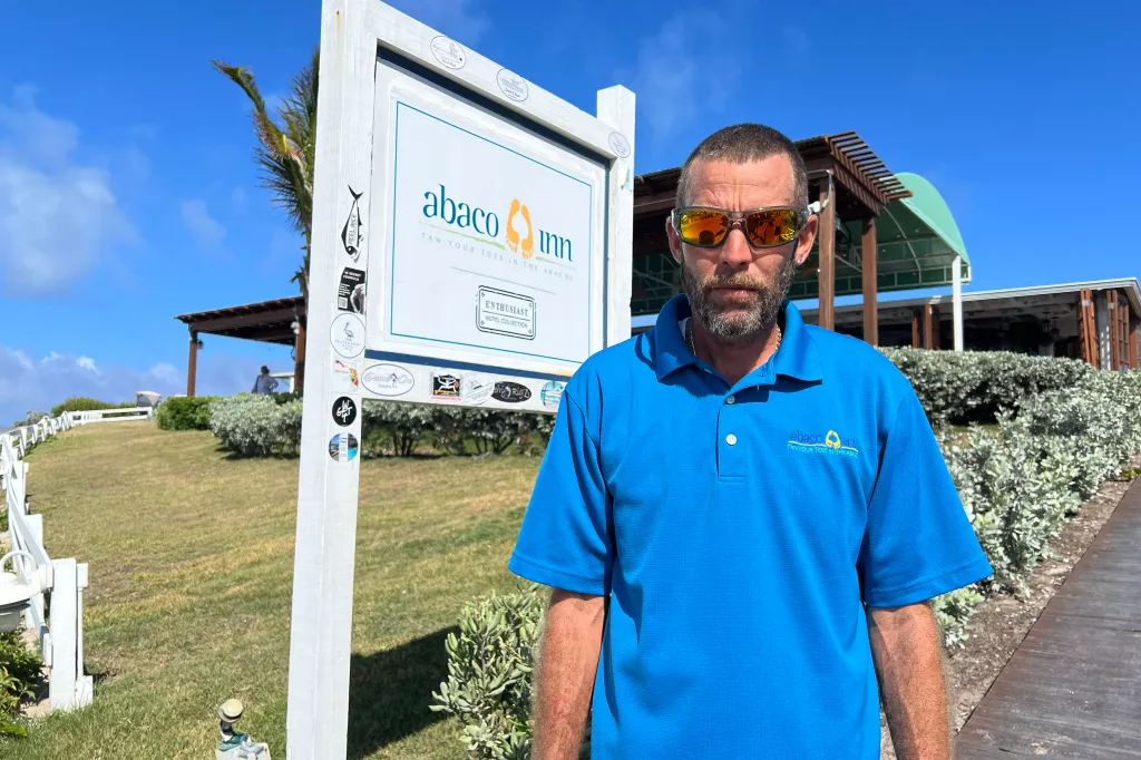 Ken, the bartender who served Brian and Lynette Hooker, stands by the "Abaco Inn" sign.