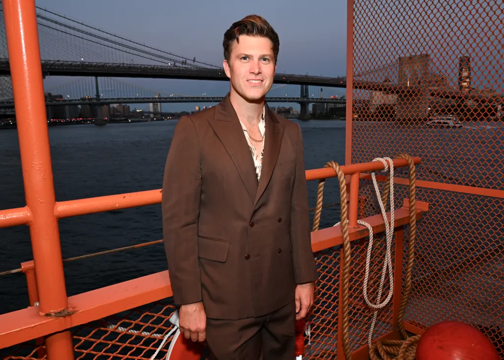 Colin Jost in a brown suit on the Staten Island Ferry for Tommy Hilfiger's Spring 2025 fashion show.