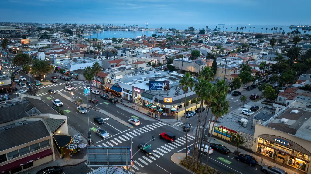 Aerial view of Belmont Shore, California at dusk, with streets, businesses, and homes leading to the bay and ocean.