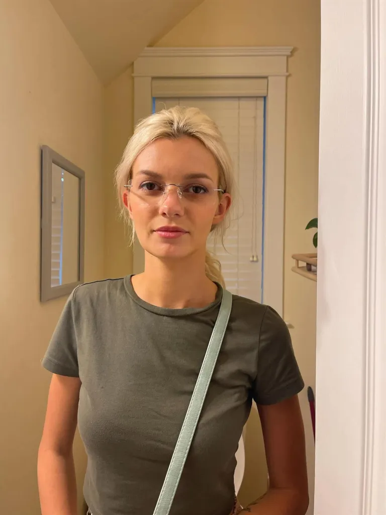 Iryna Zarutska, a woman with blonde hair, wearing glasses and a green t-shirt, looks directly at the camera.