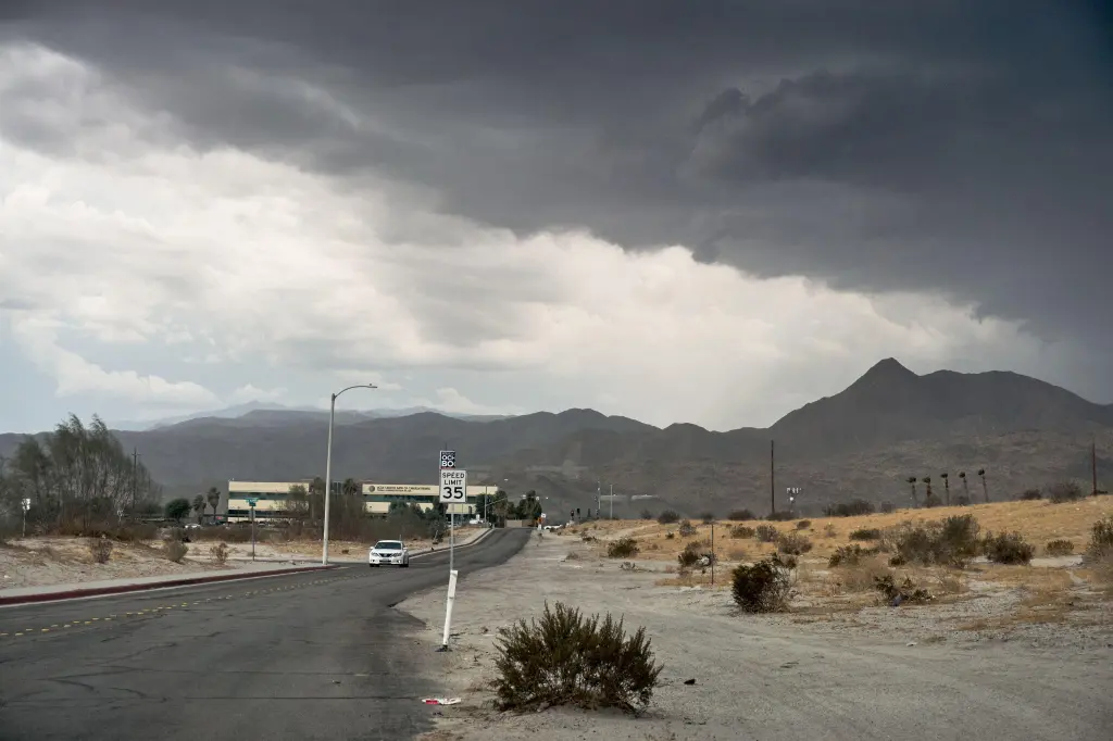 Dark monsoon clouds over Palm Springs, California, with a mountain range in the background and a road leading toward the Agua Caliente Band of Cahuilla Indians Tribal Administration Plaza.