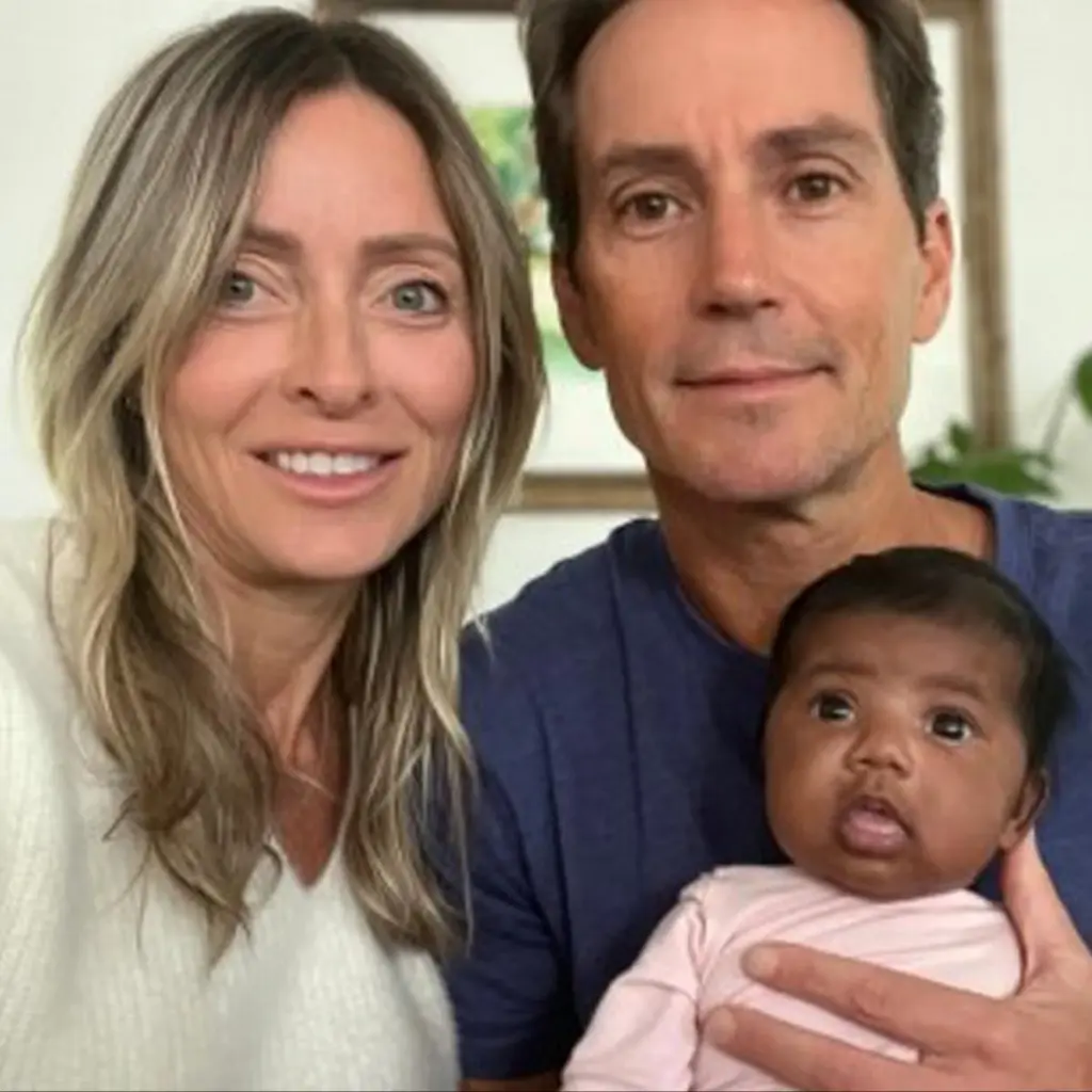 A couple, identified as the Florida couple, pose with a baby.