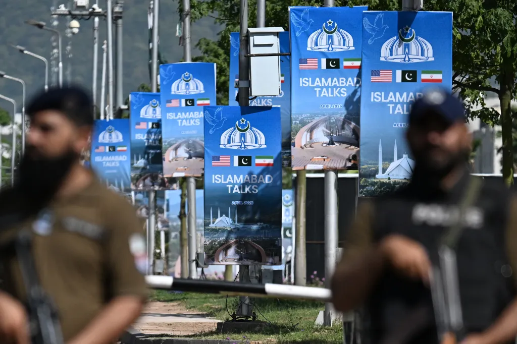Security personnel stand guard near banners for the "Islamabad Talks" with flags of the US, Pakistan, and Iran.