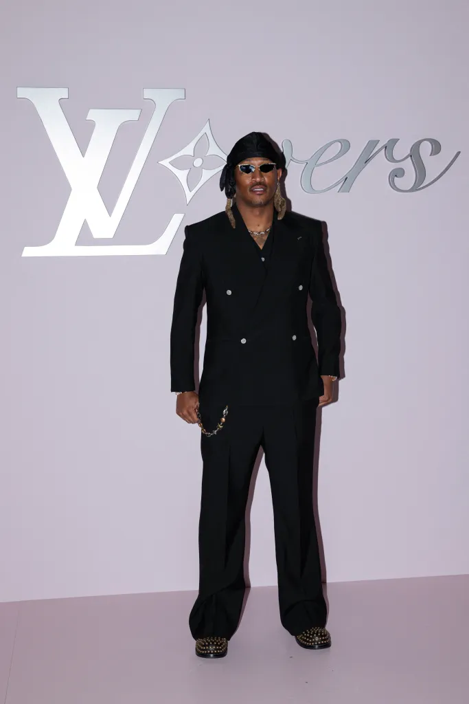 US rapper Future poses in a black suit with a black durag and sunglasses against a pink wall with Louis Vuitton "Lovers" branding.