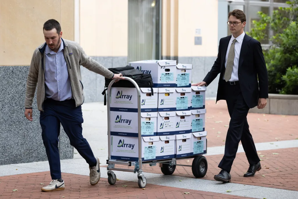 Two men push a trolley stacked with boxes labeled "Array," belonging to MoloLamken, a firm representing Elon Musk in a lawsuit against OpenAI.