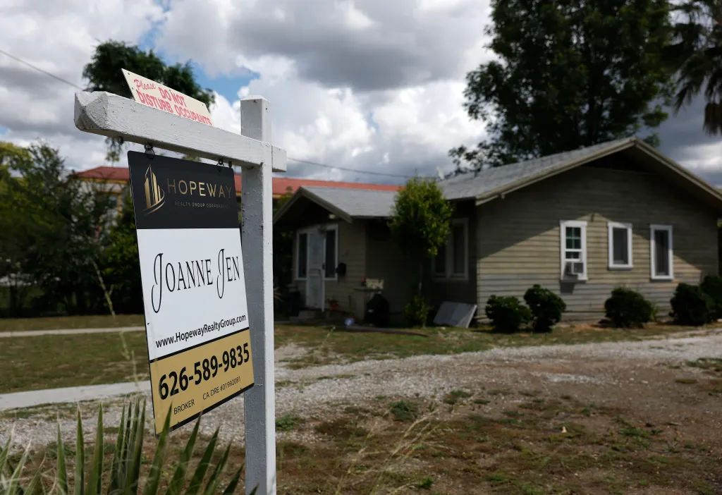 A "for sale" sign in front of a house, indicating declining existing home sales.