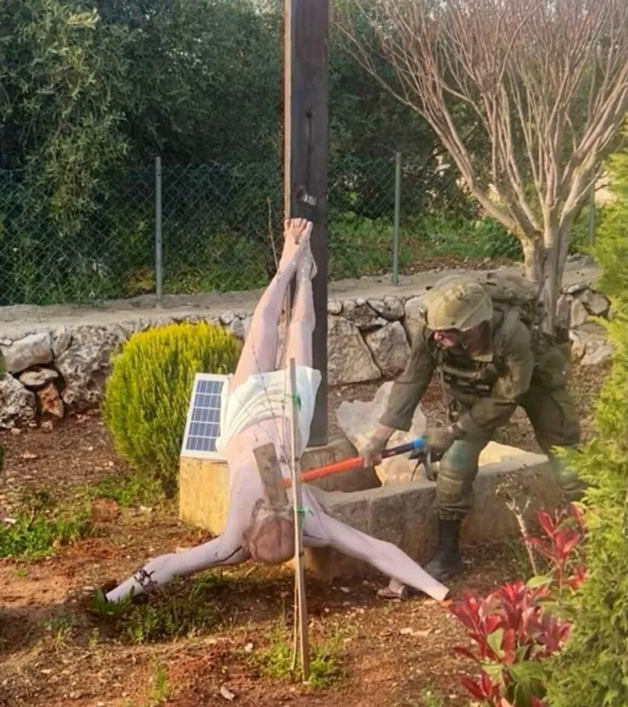 An Israeli soldier damages the head of a statue of Jesus in Debel.