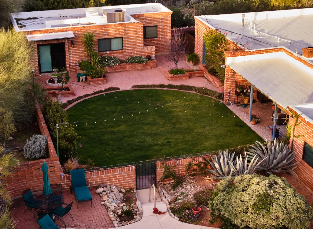An aerial view of Nancy Guthrie’s Tucson, Arizona home, showing the backyard with a manicured lawn, brick patio, and desert plants.