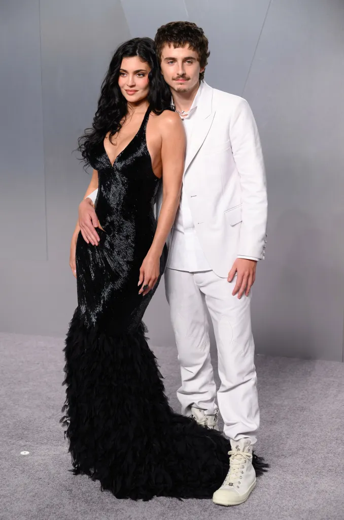 Kylie Jenner in a black dress and Timothée Chalamet in a white suit pose together at the Vanity Fair Oscar Party.