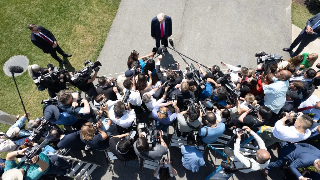Aerial view of Donald Trump speaking to a large group of media members.