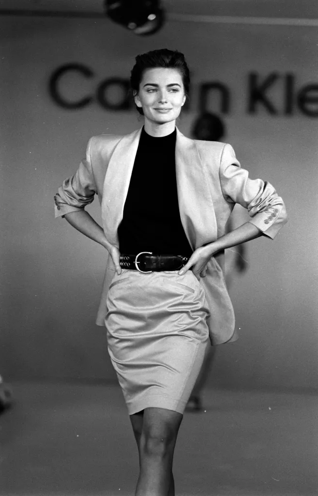 Paulina Porizkova in a Calvin Klein blazer, black turtleneck, belted skirt.