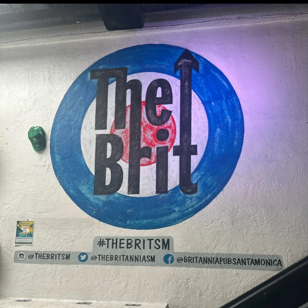 The Brit Pub logo painted on a wall, with social media handles underneath.
