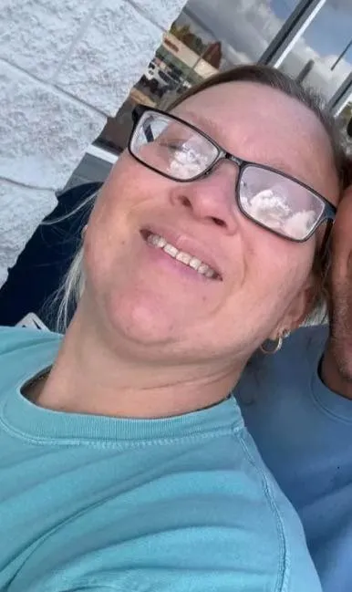 Lisa Gail Fields, a 46-year-old woman, smiling while wearing glasses and a turquoise shirt.