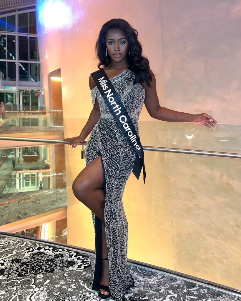 A woman wearing a "Miss North Carolina" sash and a sparkling, off-the-shoulder gown with a high slit.