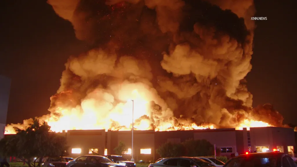 A massive fire with thick smoke engulfing a building at night.