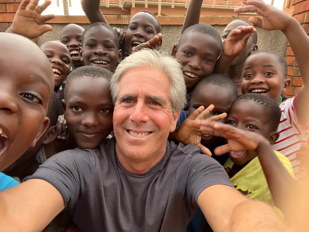Selfie of Barry Hoffner surrounded by smiling children in Uganda.