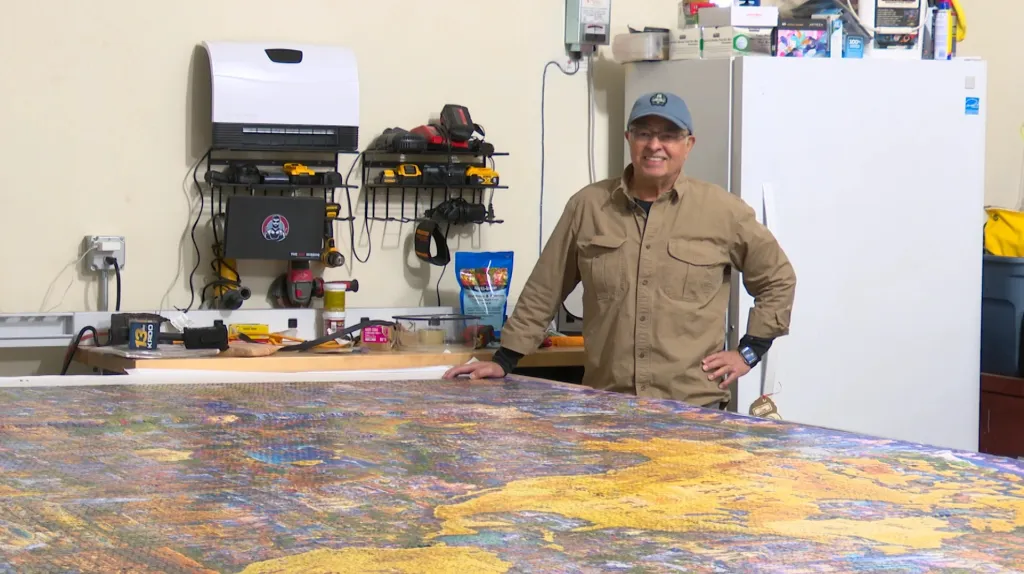 A man standing next to a large abstract painting.
