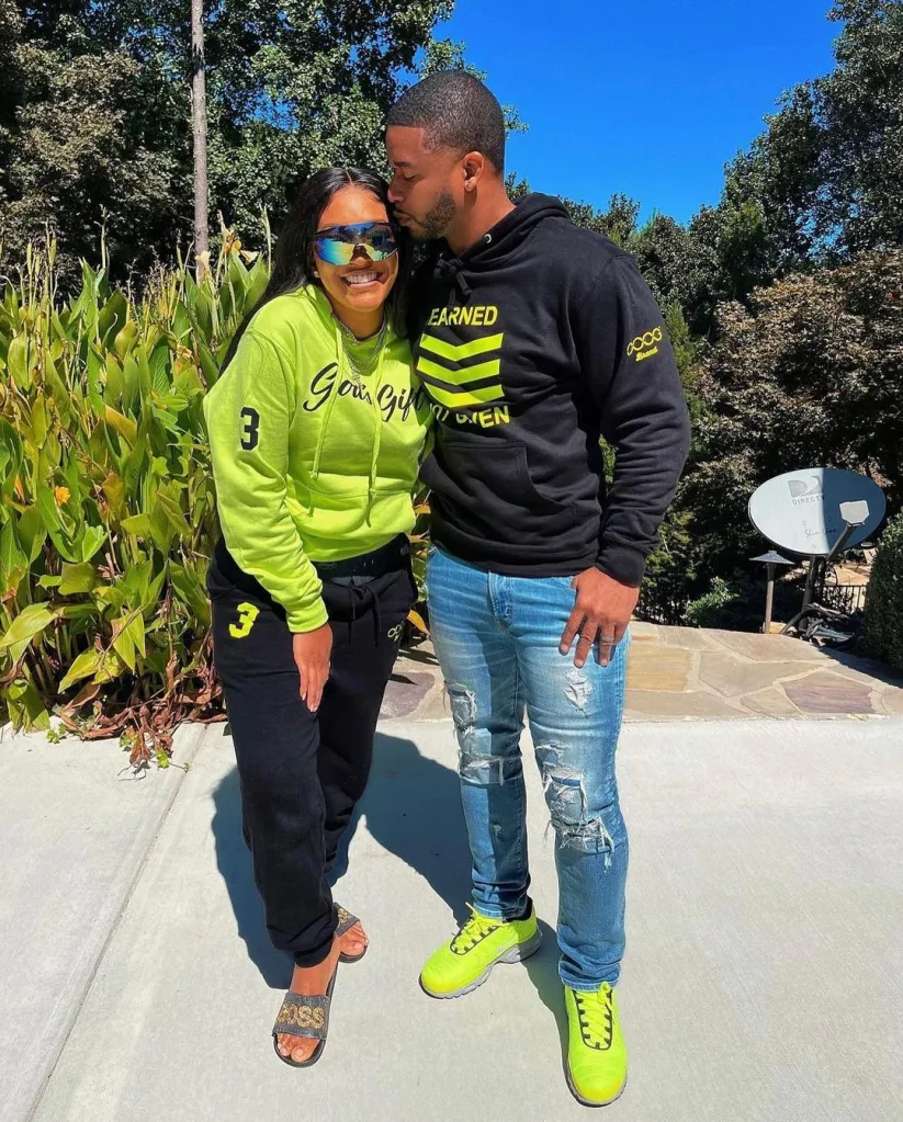 A man kissing a woman on the forehead, both wearing matching neon green and black outfits.