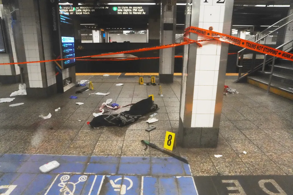 A New York subway platform with crime scene tape reading "STABBING WORK IN PROGRESS" and "TRAINS NOT STOPPING," with discarded items and forensic markers on the floor.