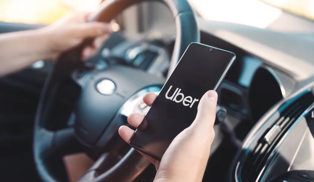 Uber driver holding a smartphone in a car.